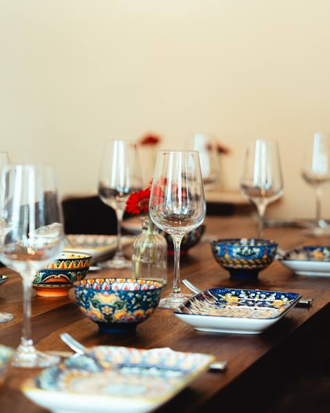 Gedeckter Tisch mit Weingläsern und bunt bemalten Schalen