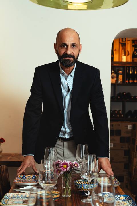 Shah Fahimi, Inhaber von Mana Mana, steht lächelnd hinter einer gedeckten Tafel